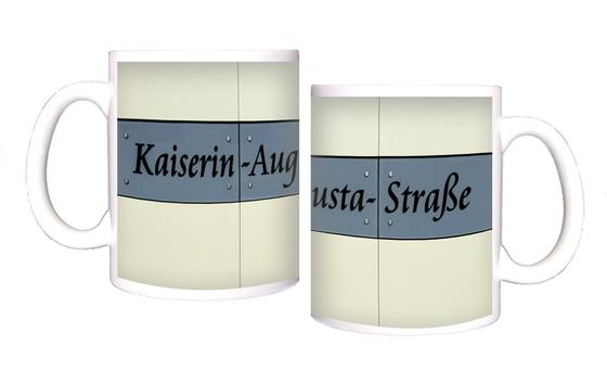 U-Bahnhof Kaiserin-Augusta-Straße Kaffeetasse - Schwarze, geschwungene Schrift auf grau-blauem Schild vor weißem Fliesenhintergrund