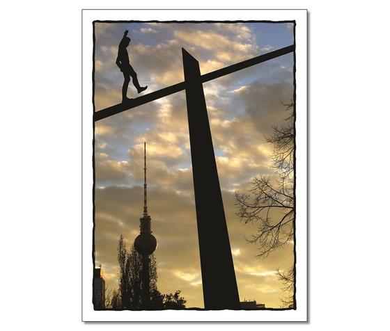 Foto einer monumentalen Skulptur im Sonnenuntergang mit Fernsehturm im Hintergrund. Balanceakt. 