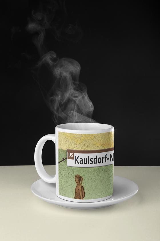 U-Bahnhof Kaulsdorf-Nord Kaffeetasse, schwarze Schrift auf weißem Streifen über gelb grünem Hintergrund mit braunen Siluetten von Menschen