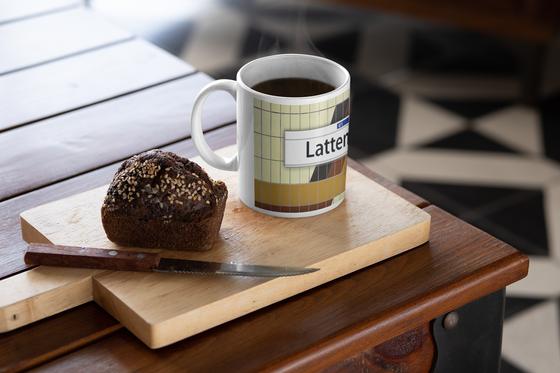 S-Bahn Hamburg Kaffeebecher Kaffeetasse S-Bahnhof Lattenkamp beige Fliesen mit orang, rot gelbem Muster, darüber weißes Schild mit schwarzer Schrift tom bäcker, Geschenkidee, 