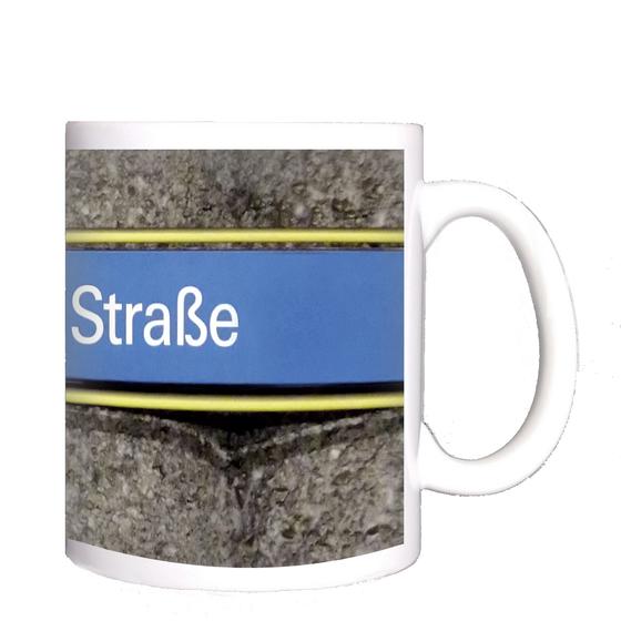 U-Bahnhof Basler Straße Kaffeetasse - weiße Schrift auf hellblauem Schild, gelb umrandet, vor grauer Säulenwand