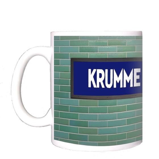 U-Bahnhof Krumme Lanke Kaffeetasse - weiße Schrift auf blauem Schild, vor grün-blauer Fliesenwand