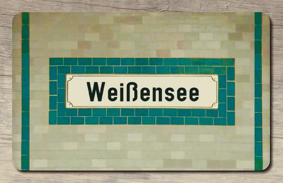 S- und U-Bahnhof Weißensee Frühstücksbrettchen - weißes Schild mit schwarzer Schrift auf petrol-farbige Flieseneinrahmung