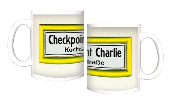 U-Bahnhof Checkpoint Charlie Kochstrasse Kaffeetasse - schwarze Schrift auf weißem Schild mit gelbem Rahmen, vor weisser Wand