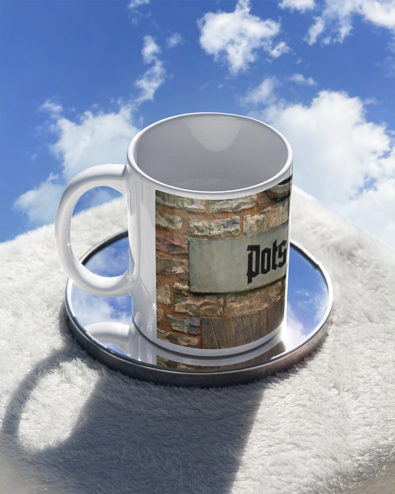 S-Bahnhof Potsdam Kaffetasse, schwarze Frakturschrift auf grauemhintergrund auf Backsteinwand über Torbogen