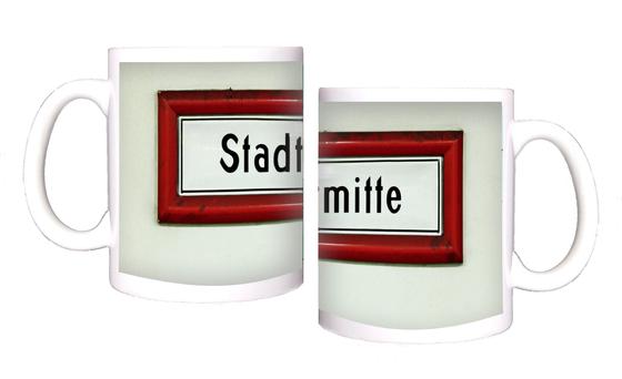 U-Bahnhof Stadtmitte Kaffeetasse - schwarze Schrift auf weißem Schild, mit rotem dickem Rahmen, vor weißer Wand