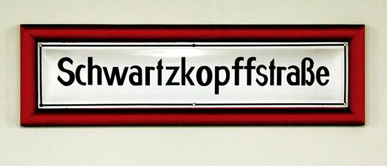 U-Bahnhof Schwartzkopffstraße Kaffeetasse - schwarze Schrift auf weißem, traditionellem U-Bahnschild mit dickem, rotem Rahmen