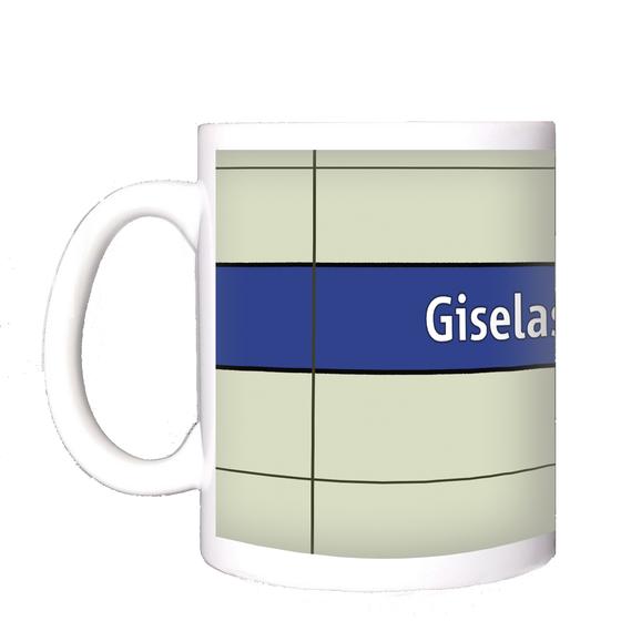 U-Bahnhof Giselastraße Kaffeetasse - weiße Schrift auf blauem Streifen, vor weißem Plattenhintergrund