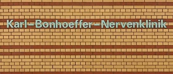 U-Bahnhof Karl-Bonhoeffer-Nervenklinik Kaffeetasse - weiße Lettern auf gelbem Backsteinhintergrund mit rötlich-braunen Streifen