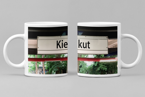 U-Bahn Kaffeebecher Kaffeetasse U-Bahnhof Kiekut schwarze schrift auf weißem frei schwebendem schild im hintergrund Bäume und Geäst
