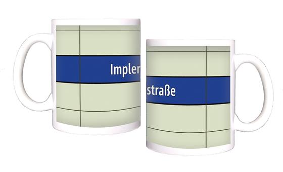 U-Bahnhof Implerstraße Kaffeetasse - weiße Schrift auf blauem Streifen, vor weißem Plattenhintergrund
