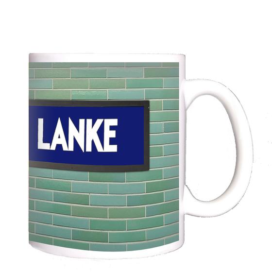 U-Bahnhof Krumme Lanke Kaffeetasse - weiße Schrift auf blauem Schild, vor grün-blauer Fliesenwand