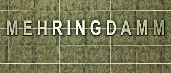 U-Bahnhof Mehringdamm Kaffeetasse - silberne Lettern auf grün-grauer Fliesenwand mit Steinoptik