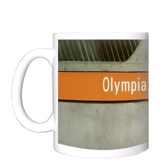 U-Bahnhof Olympiazentrum München Kaffeetasse - weiße Schrift auf orangem Schild vor grauer Betonwand
