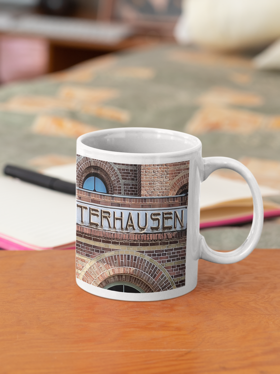 S-Bahnhof Koenigswusterhause Kaffetasse braune Schrift auf grauem Streifen an Backsteinhaus mit Fenstern