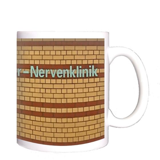 U-Bahnhof Karl-Bonhoeffer-Nervenklinik Kaffeetasse - weiße Lettern auf gelbem Backsteinhintergrund mit rötlich-braunen Streifen