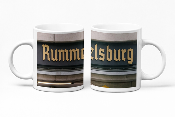 S-Bahnhof Rummelsburg - Frakturschrift in beige auf einem dunklen Schild weitere helle Streifen - Ansicht Tasse links und rechts