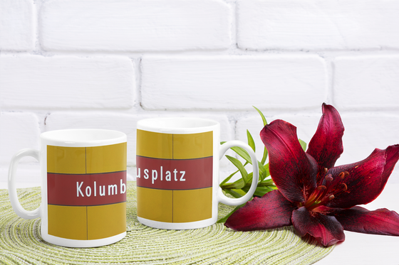 U-Bahnhof Kolumbusplatz Kaffeetasse - weiße Schrift auf dunkelrotem Streifen, vor gelber Plattenwand