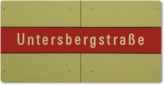 U-Bahnhof Untersbergstraße Kühlschrankmagnet - weiße Schrift auf rotem Streifen, vor beiger Plattenwand