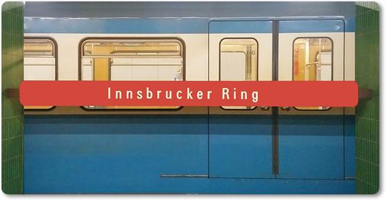 U-Bahnhof Innsbrucker Ring Kühlschrankmagnet - weiße Schrift auf rotem Streifen, vor blauem U-Bahnwagon, zwischen grünen Säulen