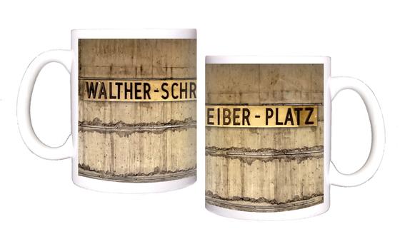 U-Bahnhof Walther-Schreiber-Platz Kaffeetasse - ehemalige Stationsgestaltung, schwarze Schrift auf Messingschild vor grau-brauner Betonwand