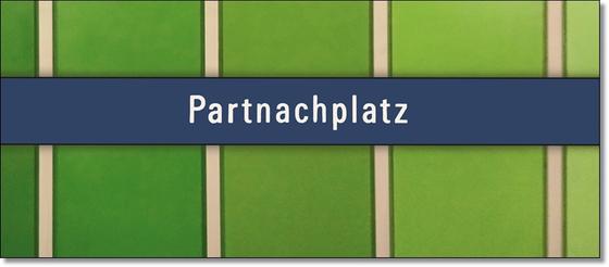 U-Bahnhof Partrachplatz - weiße Schrift auf blauem Schild vor grüner Wand mit weißen Trennbalken