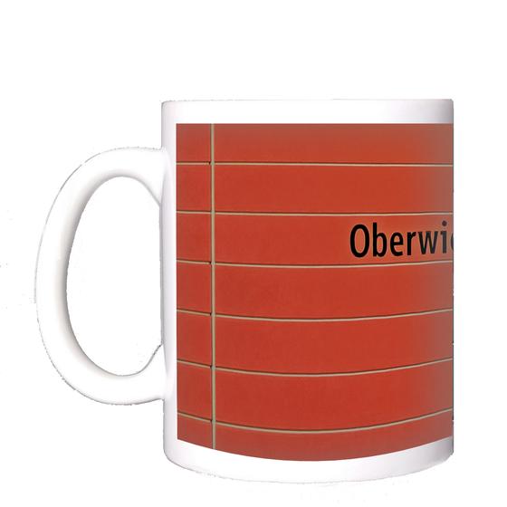 U-Bahnhof Oberwiesenfeld Kaffeetasse - schwarze Schrift auf rotem Untergrund mit grauen Querfugen