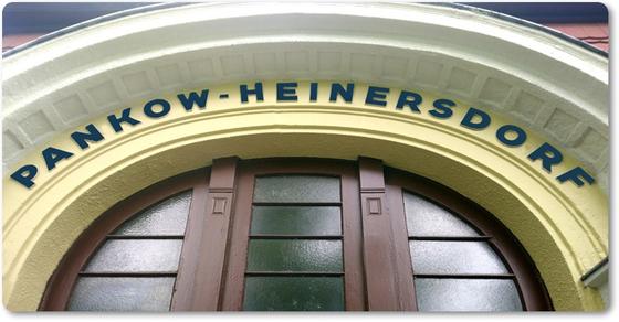 S-Bahnhof Pankow-Heinersdorf grüne Schrift auf gelbem Hintergrund über S-Bahngebäudeeingangstür