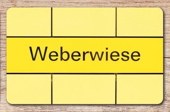 U-Bahnhof Weberwiese Frühstücksbrettchen - zitronengelber Streifen mit schwarzem Schriftzug auf hellgelbem Fliesenhintergrund