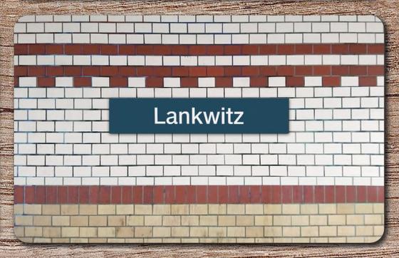S-Bahnhof Lankwitz Frühstücksbrettchen - dunkelblaues S-Bahnschild mit weißer Schrift, vor weißer Backsteinwand mit rot-braunen Backsteinlinien