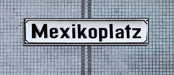 S-Bahnhof Mexikoplatz Kaffeetasse - schwarze Schrift auf weißem Metallschild, vor blauer Mosaikfliesenwand