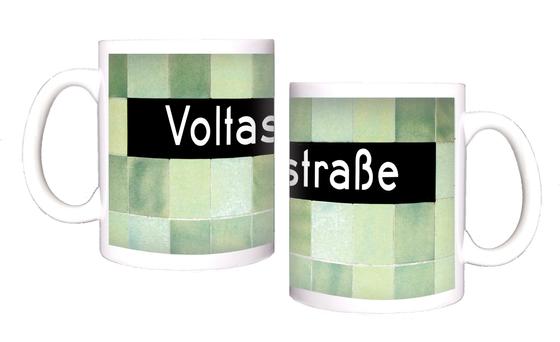 U-Bahnhof Voltastrasse Kaffeetasse - weiße Schrift auf schwarzem Schild, vor Mosaikwand in diversen Grüntönen