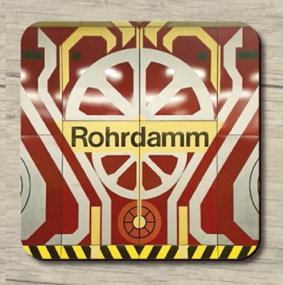 U-Bahnhof Rohrdamm - schwarze Schrift auf gelben Schild im Hintergrund aufregendes Fliesenmuster aus rot, weiß und gelb