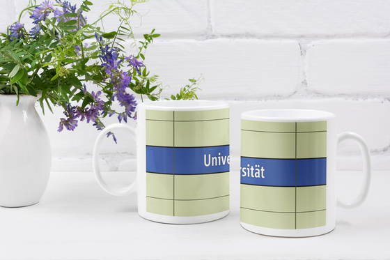 U-Bahnhof Universität Kaffeetasse - weiße Schrift auf dunkelblauem Streifen, vor weißer Plattenwand - Ansicht beide Seiten der Tasse