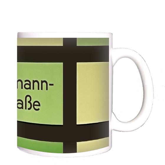 U-Bahnhof Hermannstraße Kaffeetasse - schwarze Schrift vor grün-gelbem Hintergrund mit schwarzem Gittermuster