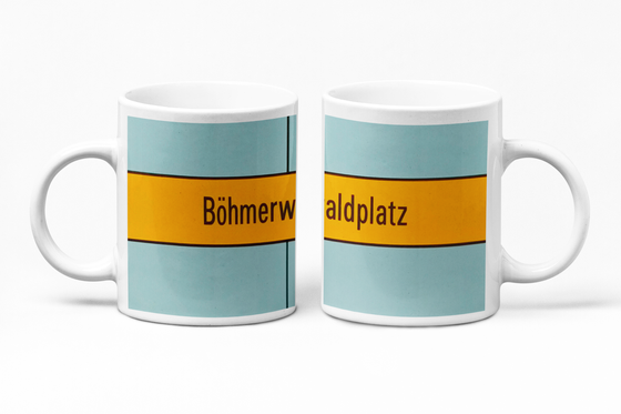 U-Bahn-Tasse München Böhmerwaldplatz der Linie U4 in der originalgetreuen Stations-Gestaltung - schwarze Schrift auf gelbem Streifen, bläulicher Hintergrund