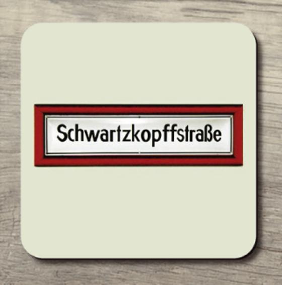 U-Bahnhof Schwartzkopffstraße Frühstücksbrettchen - weißes Schild mit schwarzer Schrift in rot-farbiger Einrahmung auf beigem Hintergrund