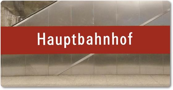 U-Bahnhof München Hauptbahnhof Kühlschrankmagnet - weiße Schrift auf dunkelrotem Streifen, vor silberner Wand im U-Bahnhof