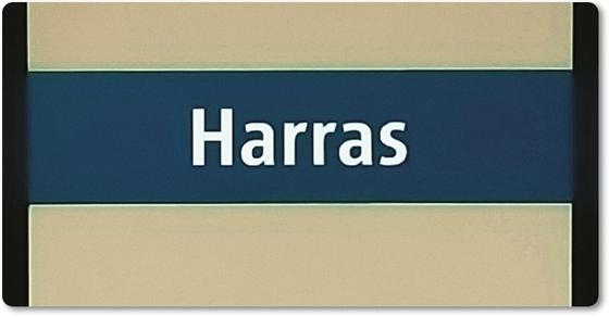 U-Bahn-Magnet München, U-banhhof Haderner Stern, Bayerns Landeshauptstadt München, Kühlschrankmagnet, tom baecker, a-point-of-viewFoto des Stationsnamens des Münchner U-Bahnhofs Harras - weiße Schrift auf blauem Streifen auf hellgrauer Wand