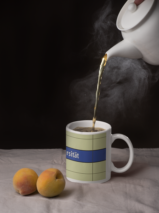 U-Bahnhof Universität Kaffeetasse - weiße Schrift auf dunkelblauem Streifen, vor weißer Plattenwand - Ansicht beide Seiten der Tasse