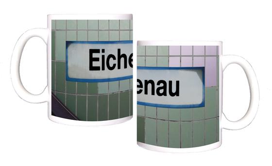 S-Bahnhof Eichenau Kaffeetasse - weißes Schild mit schwarzer Schrift und hellblauer Umrandung, auf Fliesenwand in zwei Grüntönen und weißen Fliesen