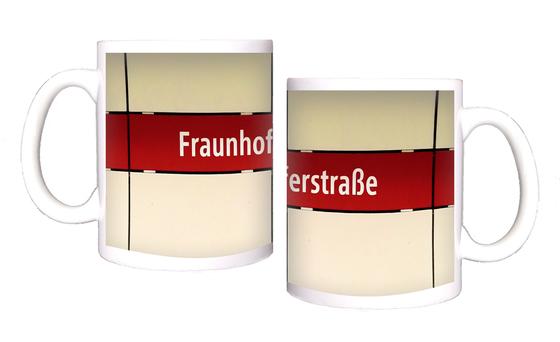 U-Bahnhof Fraunhoferstraße Kaffeetasse - weiße Schrift, auf rotem Streifen vor weißer Plattenwand