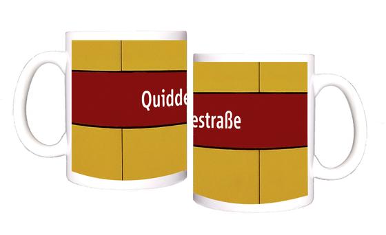U-Bahnhof Quiddestraße Kaffeetasse - weiße Schrift auf dunkelrotem Streifen, vor gelber Plattenwand