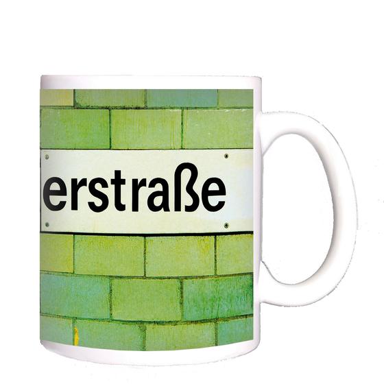 U-Bahnhof Samariterstraße Kaffeetasse - schwarzes Schild mit weißer Schrift auf grün-gelber Fliesenwand