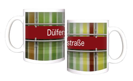 U-Bahnhof Dülferstraße Kaffeetasse - weiße Schrift auf rotem Schild auf Metallgestell, vor Streifenhintergrund in diversen Grüntönen