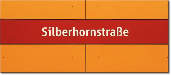 U-Bahnhof Silberhornstraße Kaffeetasse - weiße Schrift auf rotem Streifen, vor dunkelgelbem Hintergrund