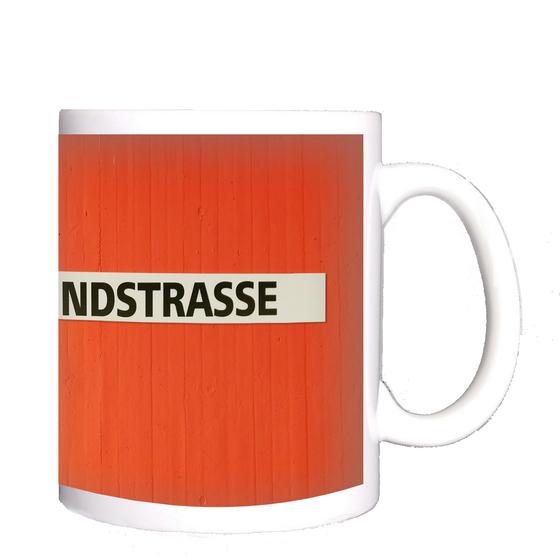 U-Bahn-Tasse Nuernberg Bauernfeindstrasse der Linie U1 in der originalgetreuen Stations-Gestaltung - schwarze Schrift auf weißem Streifen, oranger Streifenbeton Hintergrund 