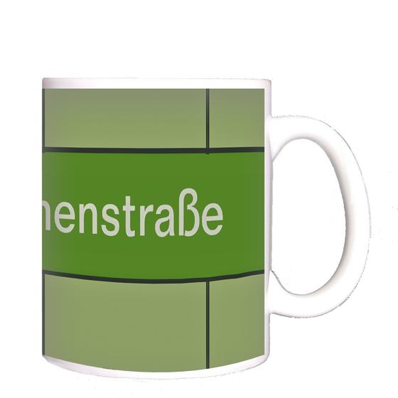 U-Bahnhof Magdalenenstraße Kaffeetasse - weiße Schrift auf grasgrünem Streifen vor waldgrünem Hintergrund, mit schwarzen Fugen