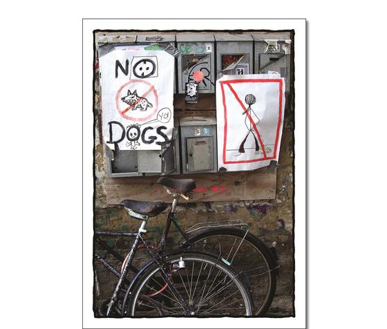 Klassische Postkarte - Foto von alten metallischen Briefkaesten. Unter diesen stehen Fahrraeder und an ihnen haengt ein gemalten Schild "No Dogs". 